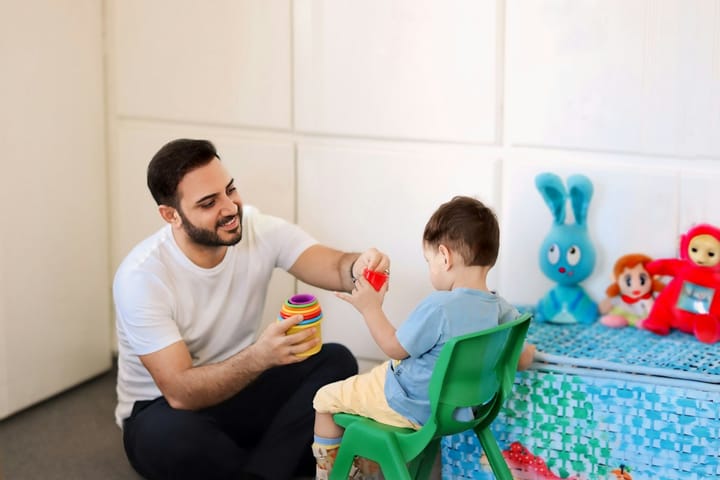 Terapeuta brincando com uma criança pequena em uma sala de atendimento