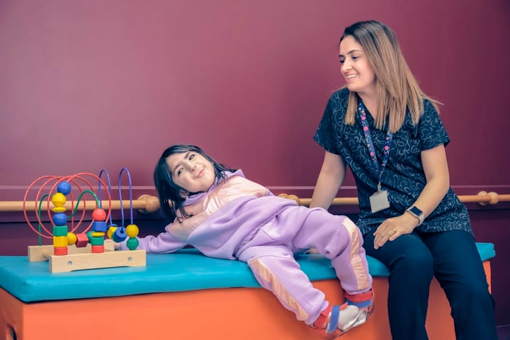 Terapeuta ao lado de uma menina em uma sala com brinquedos