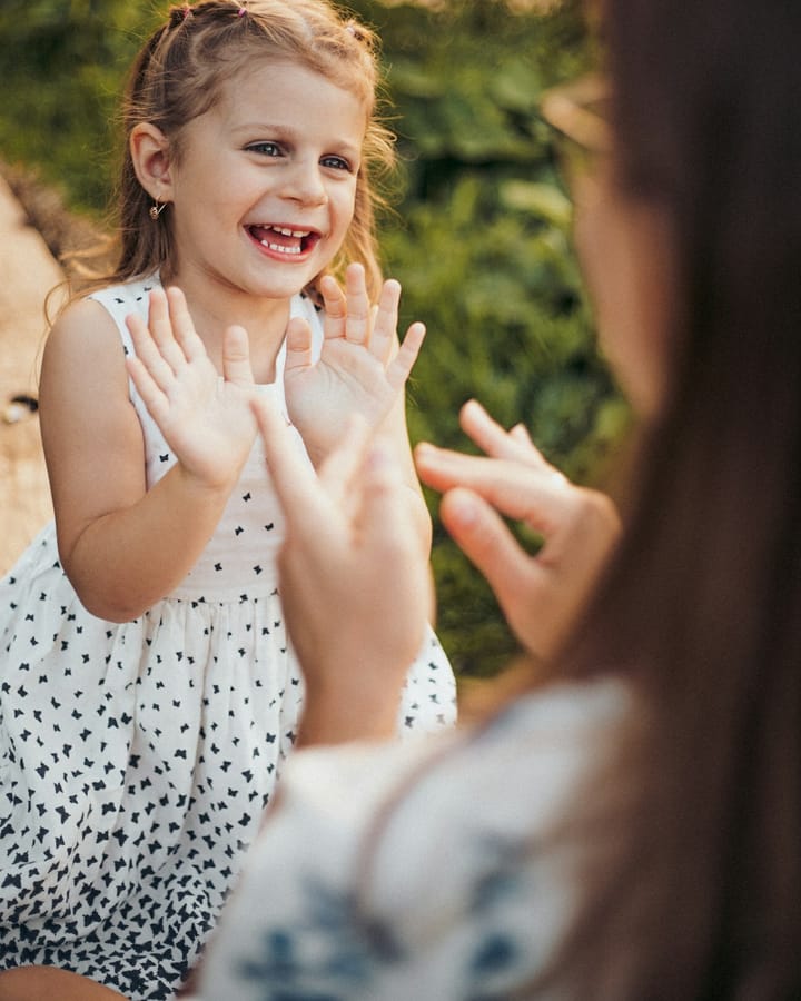 Menina sorrindo e batendo palmas durante uma atividade com a terapeuta